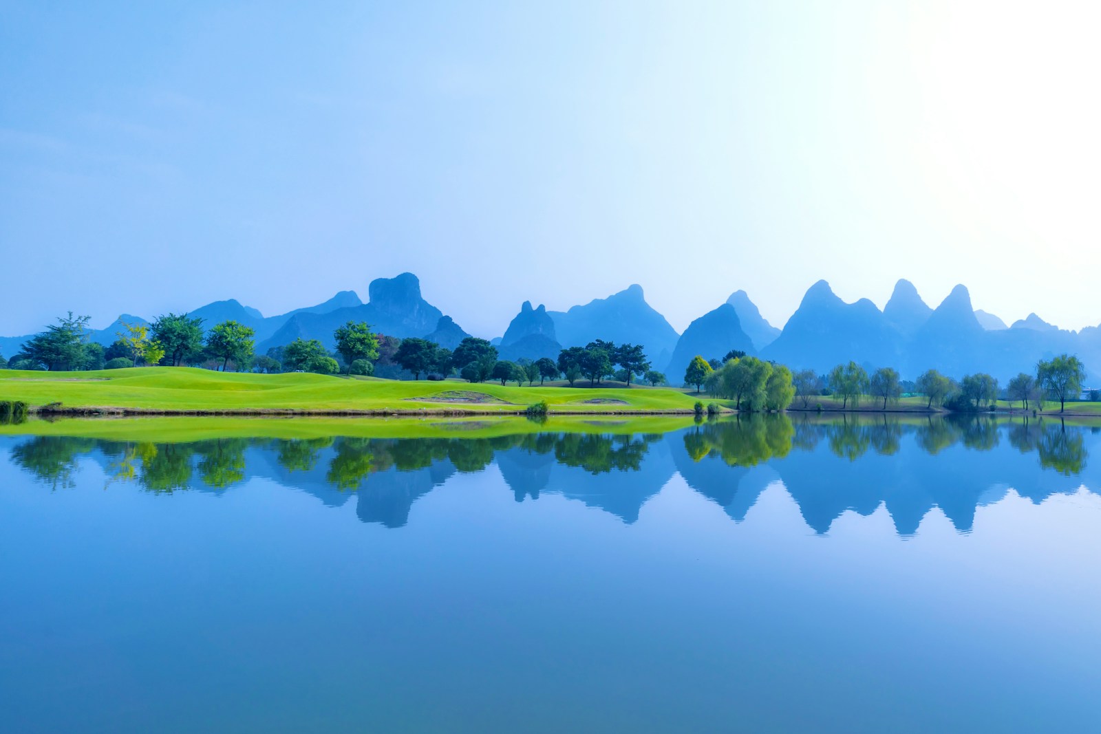 a scenic view of a golf course with mountains in the background